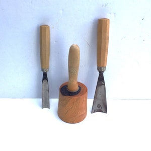 May include: Three wood carving tools with wooden handles. The tools are a mallet, a chisel, and a gouge.