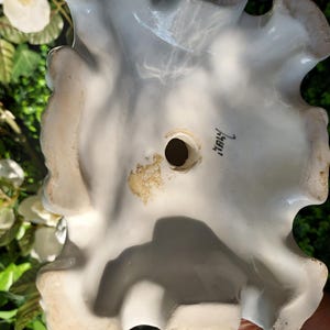 May include: White ceramic figurine with a ruffled edge and a hole in the center. The bottom of the figurine is marked "Italy".