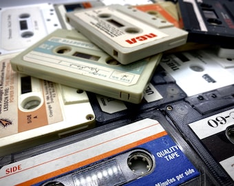 May include: A close-up of a pile of vintage audio cassette tapes. The tapes are in various colors and have different labels. Some of the tapes have the words "Side A" and "Side No." printed on them. The tapes are a popular form of music storage and are often used for listening to music on portable cassette players.