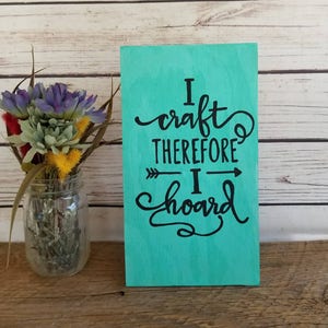 May include: A teal wooden sign with black lettering that reads "I craft therefore I hoard".