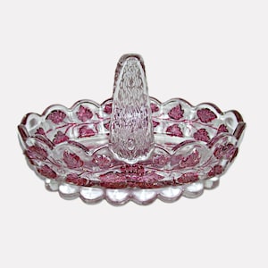 May include: Clear glass basket with a handle, featuring a scalloped rim and a decorative pattern of pink leaves and vines. The basket is designed with a clear, textured handle and a detailed leaf pattern around the rim.