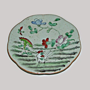 May include: A white ceramic plate with a scalloped edge, decorated with a green, red, and blue floral design and a white rooster.