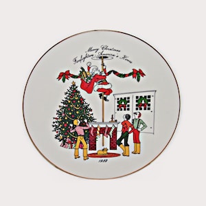 May include: A decorative plate with a gold rim featuring a Christmas scene. Santa Claus is sliding down a pole, with a Christmas tree and three children watching. The text reads "Merry Christmas Firefighters America's Heroes" and "1988".