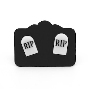 May include: A pair of black earring studs with white tombstone-shaped charms that say "RIP" on them.