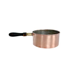 May include: A round copper saucepan with a smooth exterior finish and a metallic interior lining. The pan features a single horizontal handle made of dark brown wood, which is attached to the body with a brass-colored metal ferrule and rivets.