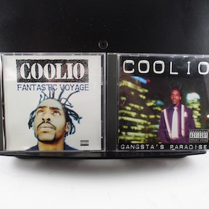 May include: Two Coolio CD albums are displayed. The album on the left is titled "Fantastic Voyage" and features a portrait of Coolio. The album on the right is titled "Gangsta's Paradise" and features Coolio in a suit.