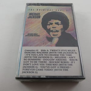 May include: A vintage cassette tape featuring Michael Jackson's album, "The Original Soul of Michael Jackson." The cover has a portrait of Jackson. The tracklist includes songs like "Dancing Machine" and "Rockin' Robin."