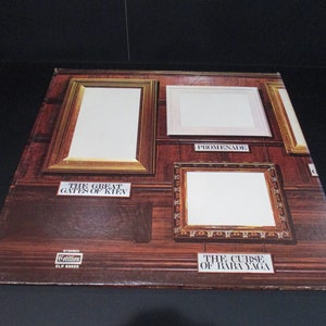 May include: A vintage vinyl record album cover featuring four empty picture frames against a wood-paneled background. The album is titled "The Great Gates of Kiev" and "The Curse of Baba Yaga" with the word "Promenade" written below one of the frames.