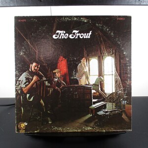 May include: A vintage vinyl record album cover featuring a band called "The Trout". The cover art shows four people in a dimly lit room with a rocking horse and a chest. The album is in stereo and has the number SE-4392 printed on the cover.