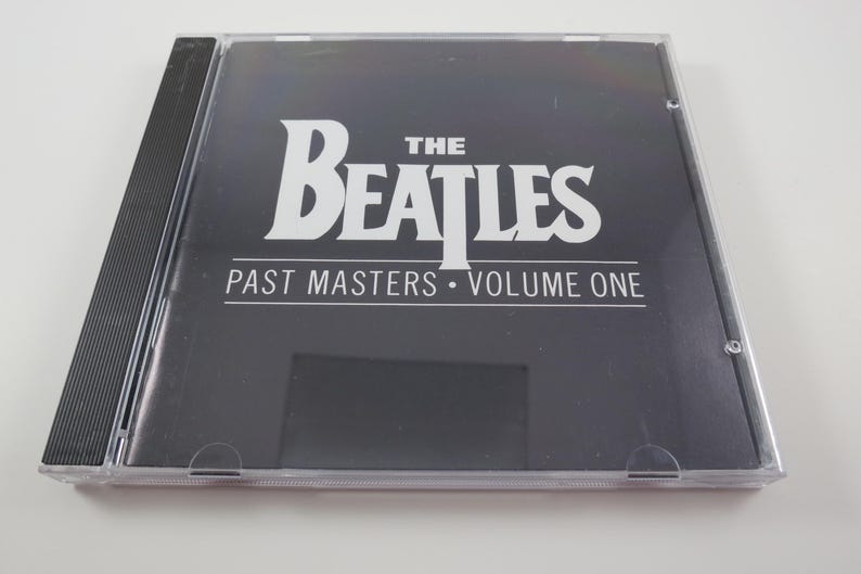 May include: A CD case for "The Beatles: Past Masters, Volume One." The album cover is black with white text. The band's name is in large, bold letters. The CD case is clear plastic.