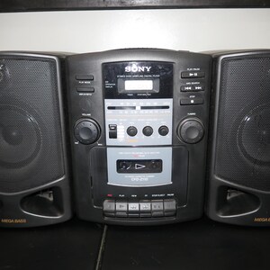 May include: A black Sony stereo boombox with two speakers and a central unit. The speakers are on either side of the unit, with the word "SONY" printed on each speaker. The central unit has a cassette player, radio, and digital display.