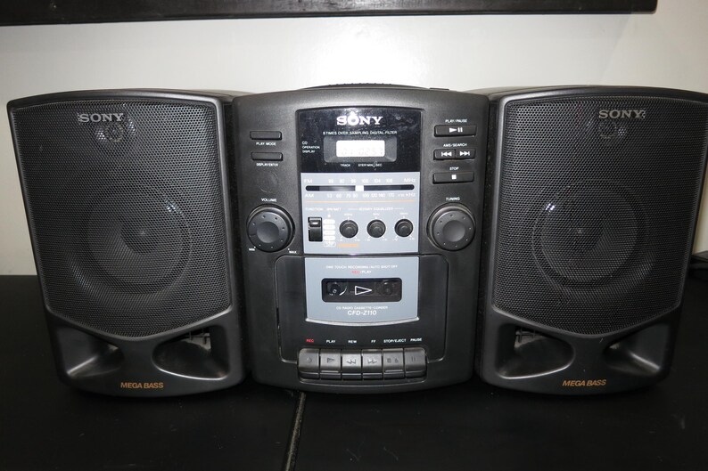 May include: A black Sony stereo boombox with two speakers and a central unit. The speakers are on either side of the unit, with the word "SONY" printed on each speaker. The central unit has a cassette player, radio, and digital display.
