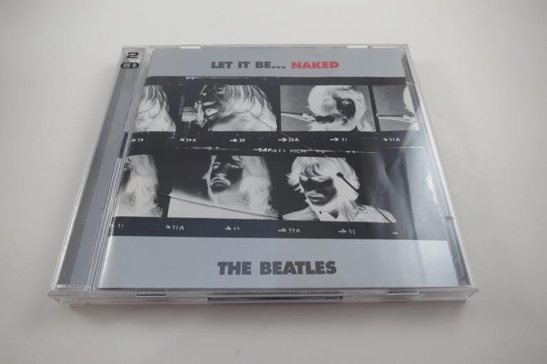 May include: A CD case for "Let It Be... Naked" by The Beatles. The album cover features a series of black and white images of the band members. The text "LET IT BE... NAKED" is at the top, with "THE BEATLES" at the bottom.