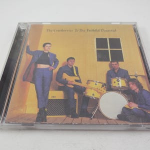 Puede incluir: Una caja de CD con fondo amarillo y una banda de cuatro personas. La banda se llama "The Cranberries" y el &aacute;lbum se llama "To The Faithful Departed".