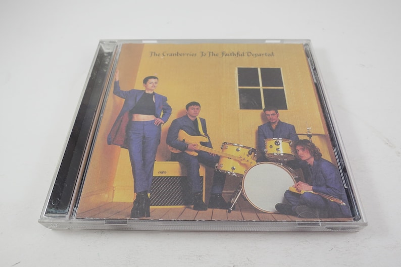 Puede incluir: Una caja de CD con fondo amarillo y una banda de cuatro personas. La banda se llama "The Cranberries" y el &aacute;lbum se llama "To The Faithful Departed".