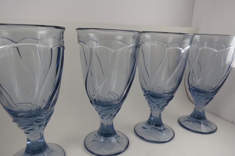 Pu&ograve; includere: Quattro bicchieri a stelo azzurri. I bicchieri hanno una coppa a forma di tulipano con un motivo decorativo e una base arrotondata. I bicchieri sono realizzati in un materiale di vetro trasparente.