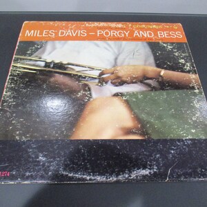May include: Vintage vinyl record album cover for Miles Davis' "Porgy and Bess." The cover features a photograph of a person playing a brass instrument. The album title is in orange text. The album's catalog number is CL 1274.