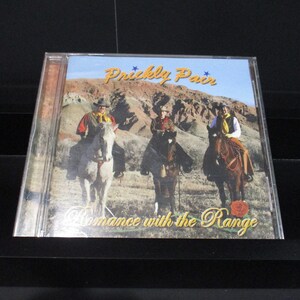 May include: A CD case with a colorful image of three cowboys on horseback in a desert landscape. The album title is "Prickly Pair Romance with the Range".