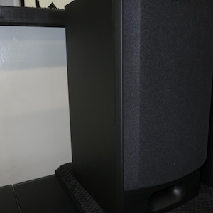 May include: Two black tower speakers with a textured front panel. The speakers are rectangular with rounded edges and sit on a black base. The speakers are designed for home audio systems.