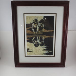 May include: Framed art print featuring two children reflected in water. The artwork has a sepia-toned palette with dark brown and black accents. The frame is a dark reddish-brown color.