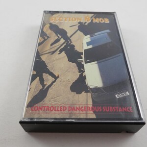 May include: A Section 8 Mob cassette tape with the album title "Controlled Dangerous Substance." The cover art features silhouetted figures and a vehicle. The cassette is in a clear plastic case.