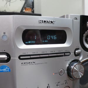 以下が含まれることがあります： 1と0.46を表示するデジタルディスプレイを備えたマルチディスクCDプレーヤー付きのシルバーのソニー製ステレオシステム。フロントパネルには、大きな音量調節ノブ、DSGX Dynamic Sound Generator X-traのロゴ、Energy Starのステッカーが付いています。