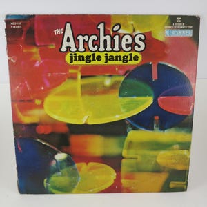 May include: Vintage vinyl record album cover for "The Archies" titled "Jingle Jangle." The cover features a colorful abstract design with red, yellow, blue, and green shapes. The album title and band name are prominently displayed.