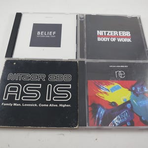 May include: Four CD cases featuring the band Nitzer Ebb. The cases display album titles such as "Belief," "Body of Work," "As Is," and "re." The album covers have text and graphic designs in various colors.