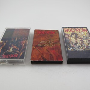 May include: Three cassette tapes with the band Skid Row printed on the front. The first tape is titled "Skid Row", the second is titled "Monkey Business", and the third is titled "Skid Row".