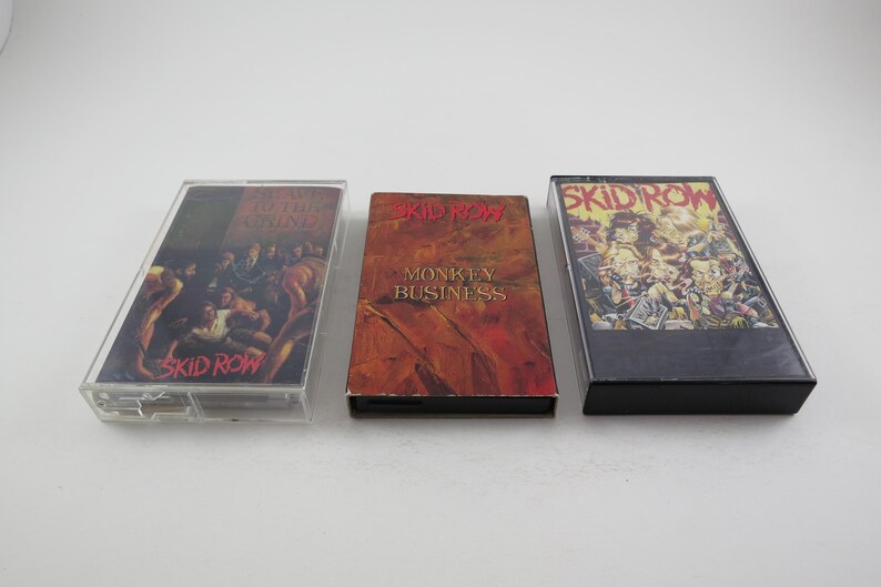 May include: Three cassette tapes with the band Skid Row printed on the front. The first tape is titled "Skid Row", the second is titled "Monkey Business", and the third is titled "Skid Row".