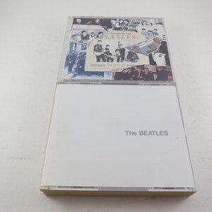 May include: Two CD cases. The top case features a collage of black and white images of The Beatles and the text "The Beatles 1962-1966". The bottom case is white with the band's name in gray text.