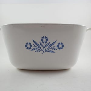 May include: White rectangular casserole dish with two handles and a blue floral design. The dish has a slightly flared shape and is made of a durable material, perfect for baking and serving. The blue floral pattern adds a touch of elegance.