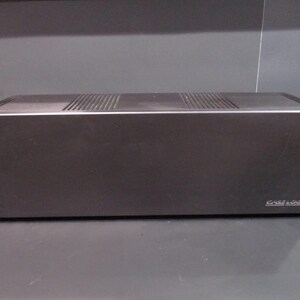 May include: A dark gray audio component with a silver trim and ventilation slots on top. The brand name "Case Logic" is visible on the lower right. The device has a rectangular shape.