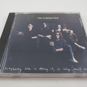 Puede incluir: Una caja de CD negra con una foto de la banda The Cranberries. La portada del &aacute;lbum presenta a los miembros de la banda en un entorno oscuro con el texto "Everybody else is doing it, so why can't we?"