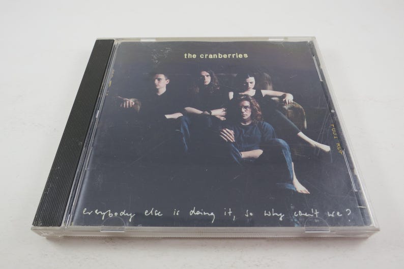 Puede incluir: Una caja de CD negra con una foto de la banda The Cranberries. La portada del &aacute;lbum presenta a los miembros de la banda en un entorno oscuro con el texto "Everybody else is doing it, so why can't we?"