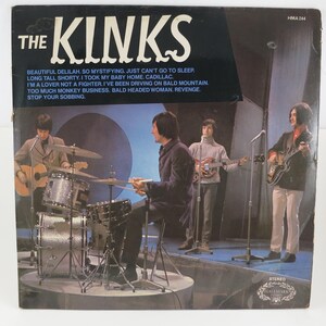 May include: Vintage vinyl record album cover for The Kinks, featuring the band performing live on stage. The album cover is black with white text, including song titles. The band members are playing instruments on a stage with a blue backdrop.