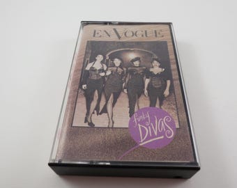 May include: A cassette tape case with a photo of the group En Vogue. The case is black with a clear plastic window showing the photo. The photo shows four women in black outfits with the text "Funky Divas" in a purple circle.
