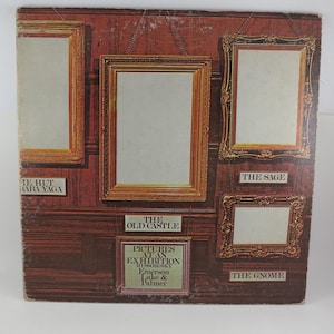 Puede incluir: Una portada de &aacute;lbum vintage con un dise&ntilde;o marr&oacute;n y dorado con im&aacute;genes enmarcadas. La portada del &aacute;lbum tiene el texto "PICTURES AT AN EXHIBITION" y los nombres Emerson, Lake & Palmer. La portada del &aacute;lbum tiene los t&iacute;tulos "THE HUT OF BABA YAGA", "THE OLD CASTLE", "THE SAGE" y "THE GNOME".