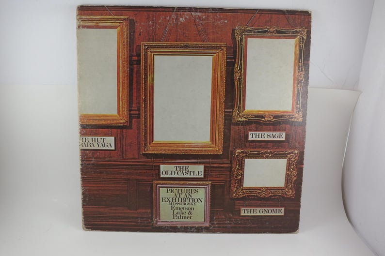 Puede incluir: Una portada de &aacute;lbum vintage con un dise&ntilde;o marr&oacute;n y dorado con im&aacute;genes enmarcadas. La portada del &aacute;lbum tiene el texto "PICTURES AT AN EXHIBITION" y los nombres Emerson, Lake & Palmer. La portada del &aacute;lbum tiene los t&iacute;tulos "THE HUT OF BABA YAGA", "THE OLD CASTLE", "THE SAGE" y "THE GNOME".
