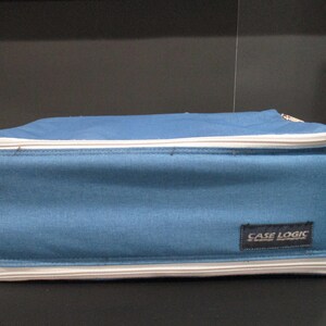 May include: A blue rectangular Case Logic bag with a white zipper and trim. The bag has a handle and a Case Logic label. The bag is made of a durable material and is designed to carry items.