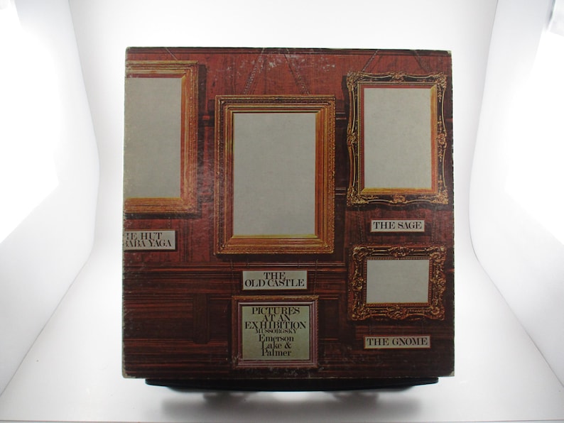 Op de afbeelding: Een vintage vinyl platenhoes met een reeks ingelijste foto's met de titels "The Hut of Baba Yaga", "The Old Castle", "The Sage" en "The Gnome". Het album is getiteld "Pictures at an Exhibition" van Emerson, Lake & Palmer.