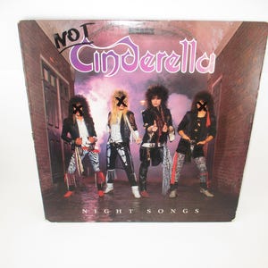 May include: A vinyl record album cover featuring the band "CINDERELLA" with the title "NIGHT SONGS". The cover art shows four band members in a dark alleyway with a brick wall in the background.