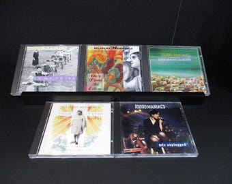 May include: A collection of six compact discs by the band 10,000 Maniacs. The titles of the albums are "In My Tribe", "Our Time In Eden", "Love Among The Ruins", "Hope Chest", and "MTV Unplugged".