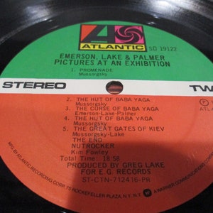 May include: A red and white vinyl record with the title "Emerson, Lake & Palmer Pictures at an Exhibition" and the text "ST-CTN-712416-PR". The record is labeled "Stereo" and "Two" and has a green and black label with the Atlantic Records logo.
