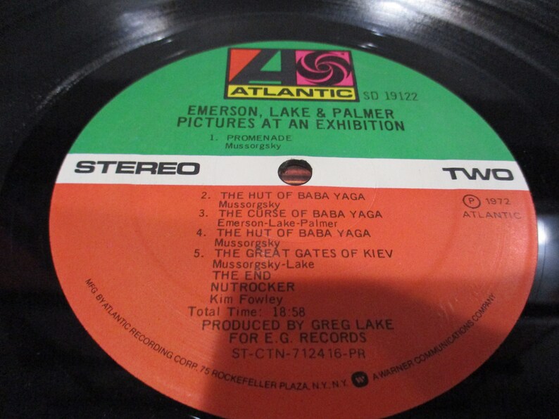 May include: A red and white vinyl record with the title "Emerson, Lake & Palmer Pictures at an Exhibition" and the text "ST-CTN-712416-PR". The record is labeled "Stereo" and "Two" and has a green and black label with the Atlantic Records logo.