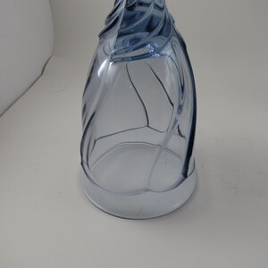 Pu&ograve; includere: Un bicchiere da vino blu in vetro con un design unico a spirale. Il bicchiere ha una base ampia e un gambo alto e curvo. Il bicchiere &egrave; in vetro trasparente con una sfumatura blu chiaro. Il bicchiere &egrave; vuoto e su una superficie bianca.