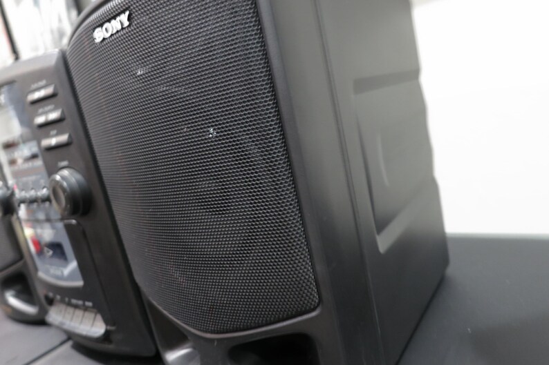 May include: Black Sony stereo system with a mesh speaker cover. The stereo has a control panel with buttons and a dial. The Sony logo is visible on the speaker.