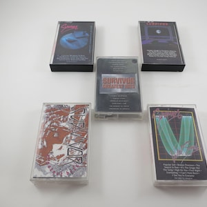 May include: Five cassette tapes with various artists and album titles. The tapes are in clear plastic cases with black and white printed labels. The titles include "Survivor", "Journey", "Greatest Hits", "Leopards", and "Sammy".