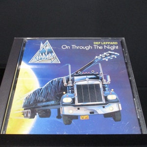 May include: A Def Leppard music cassette tape with a blue, black, and white cover featuring a semi-truck driving through the night sky with a full moon and the band's logo. The title of the album is "On Through The Night".