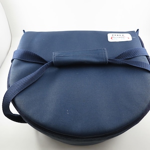 May include: A navy blue, semi-circular Pyrex carrier bag with a handle and shoulder strap. The bag has a label with the Pyrex logo. The bag is designed to carry Pyrex cookware.